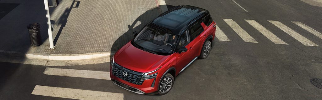 Top view of a red Nissan SUV driving through a city crosswalk.
