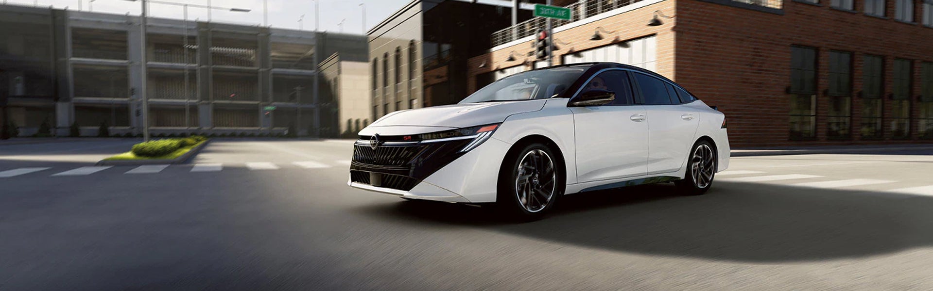 White Nissan Sentra driving through a city street.
